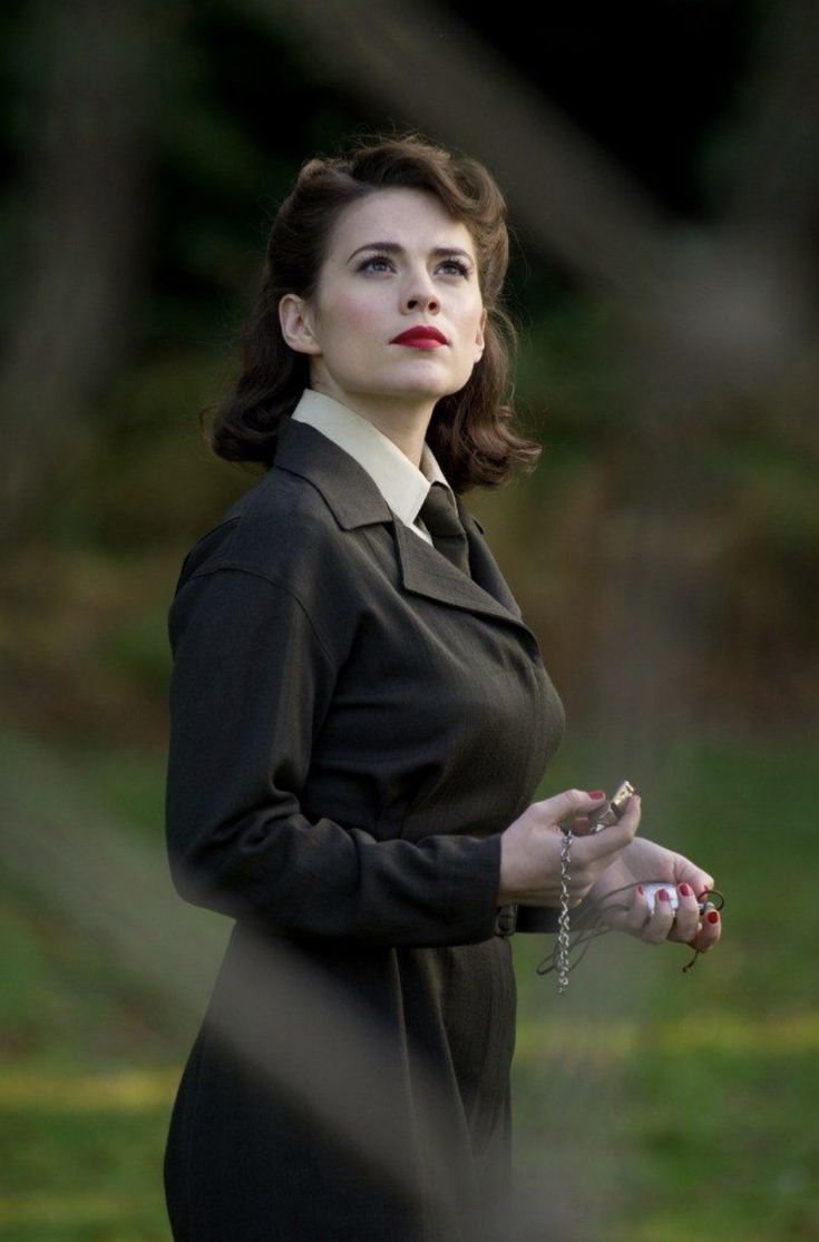 a woman in a black dress is standing outside