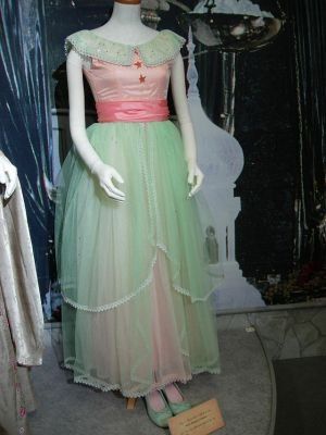 a dress on display in a museum with mannequins and dresses behind it