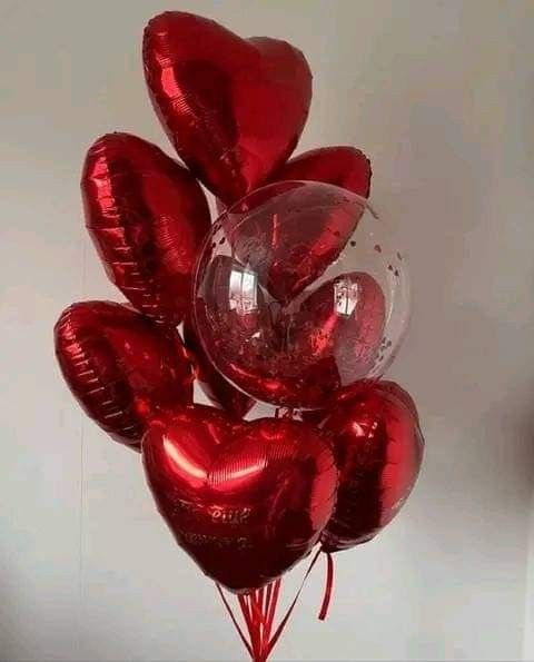 a bunch of red heart shaped balloons in the shape of hearts hanging on a wall