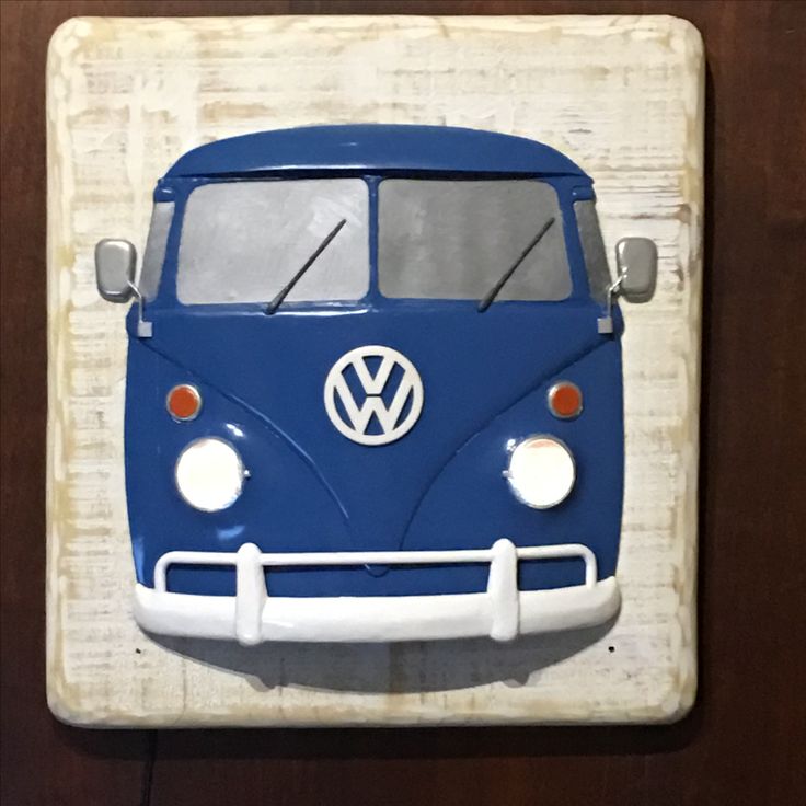 a blue and white vw bus is mounted on a wooden plaque with the word volkswagen painted on it