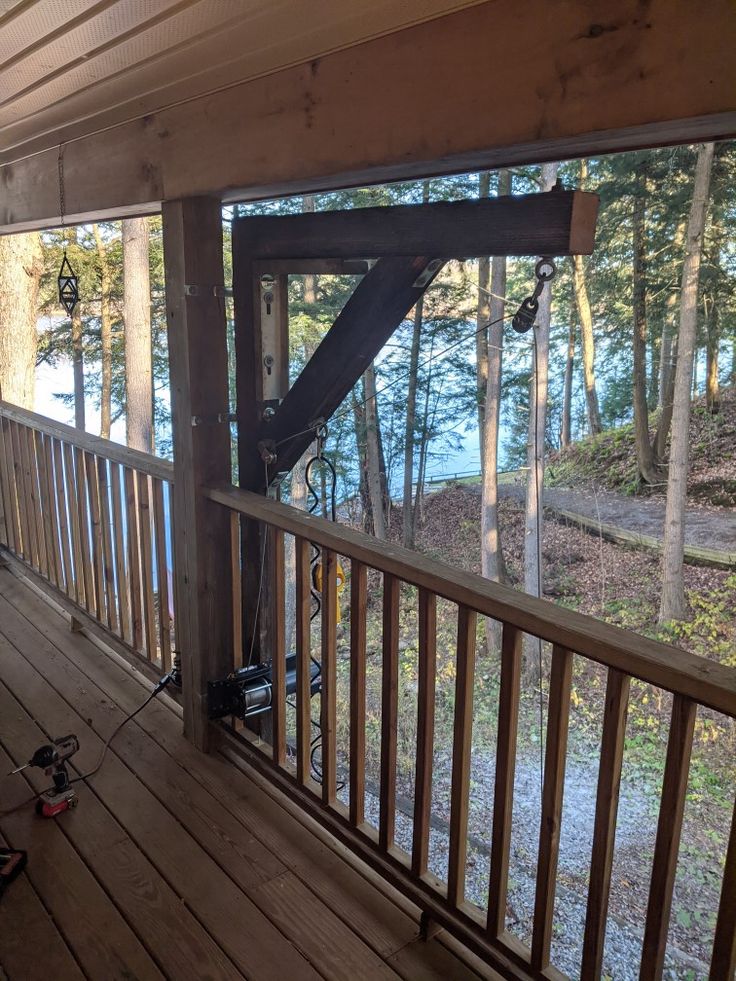 a porch with wood flooring and railings on the side of a house next to water