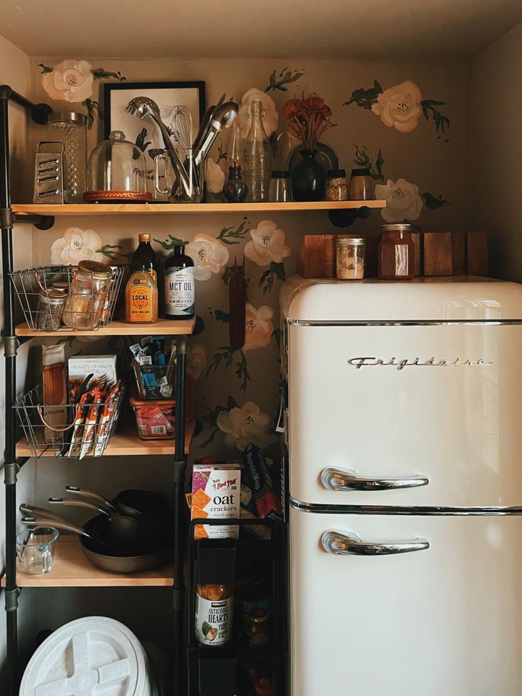 an old fashioned refrigerator in a kitchen next to a wallpapered wall with flowers on it