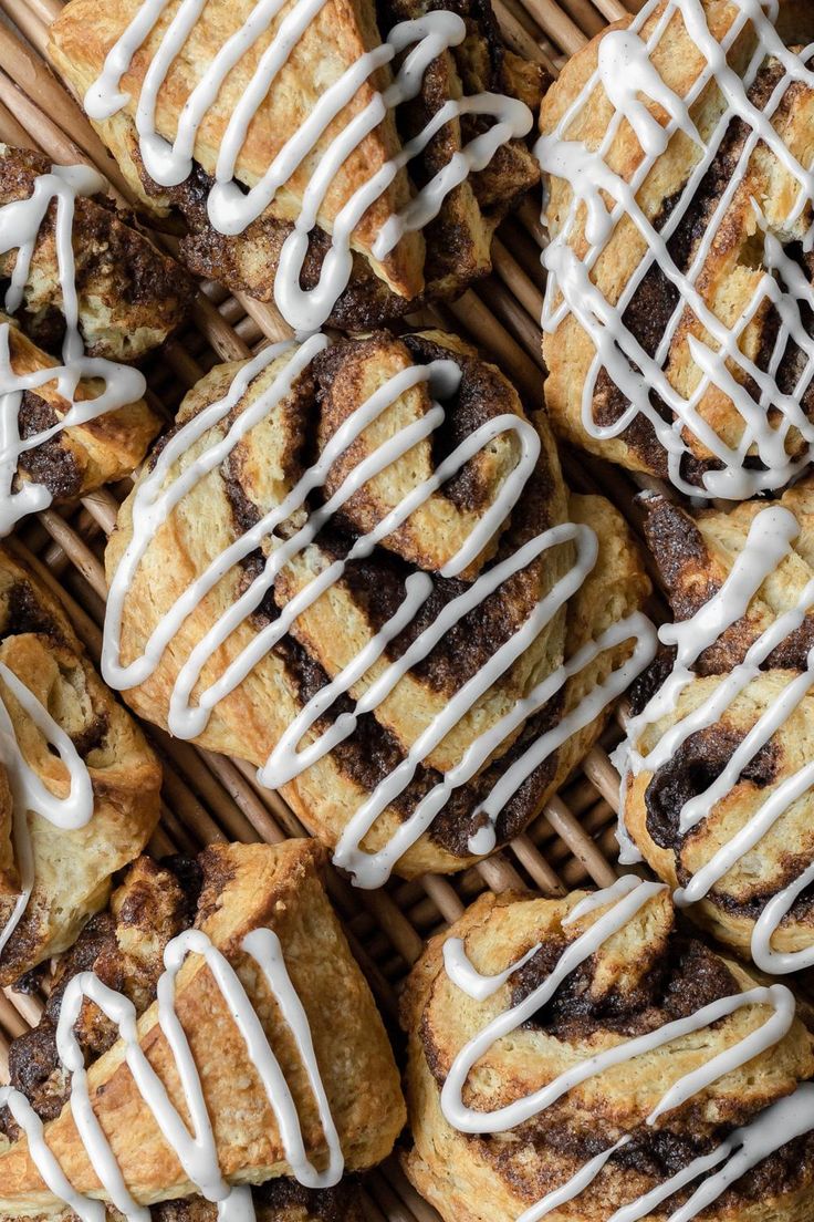 many pastries with white icing sitting in a wicker basket