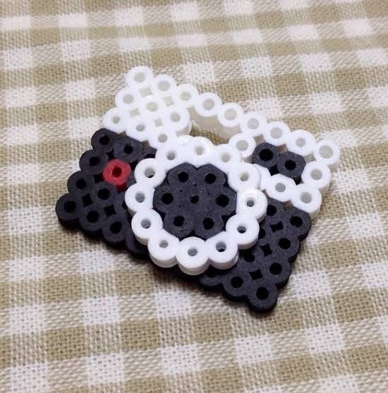 a black and white sheep brooch sitting on top of a brown checkered table cloth