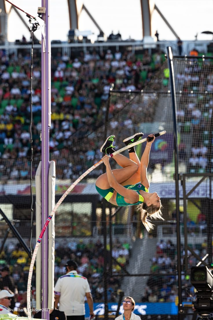 a woman jumping in the air while holding onto a pole