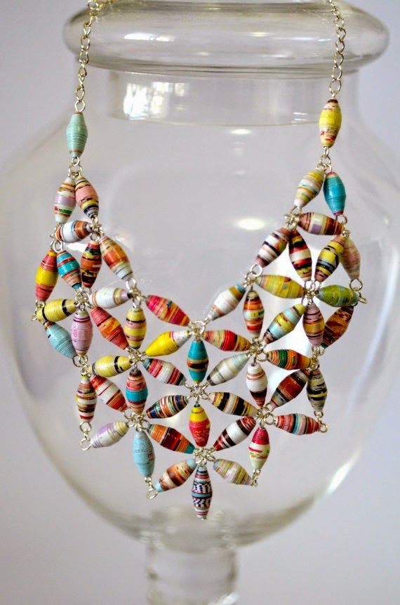 a necklace made out of shells and beads on a glass display stand in a vase