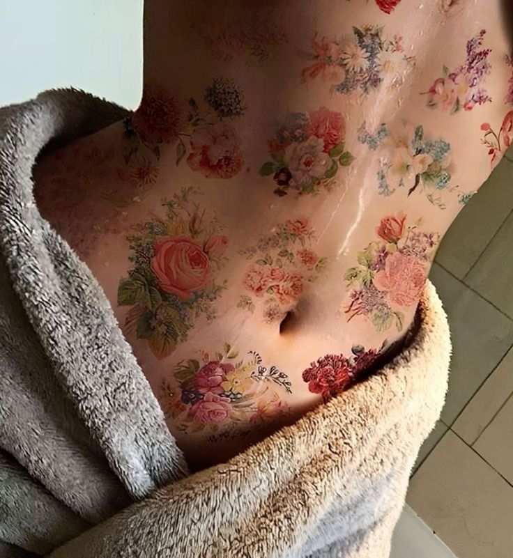 the back of a woman's body covered in flowers and leaves, with a towel draped around it