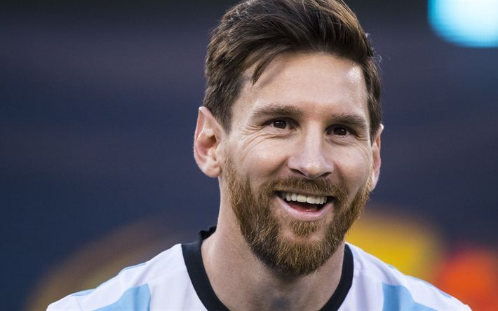 a man with a beard smiles at the camera while wearing a blue and white shirt