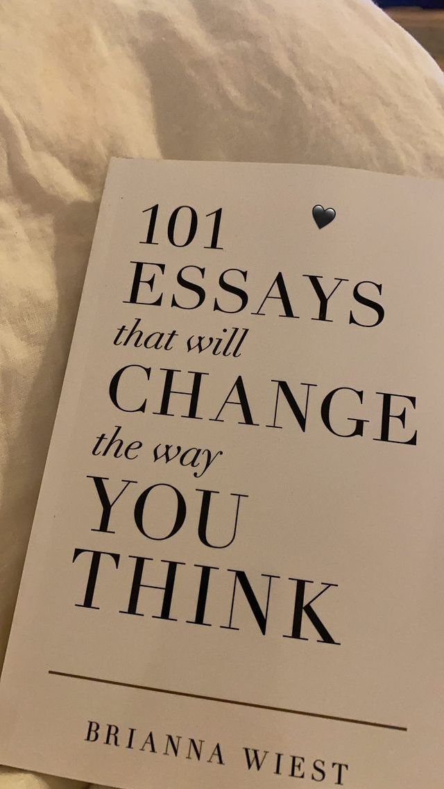 a book that is laying on top of a bed with white sheets and pillows in front of it