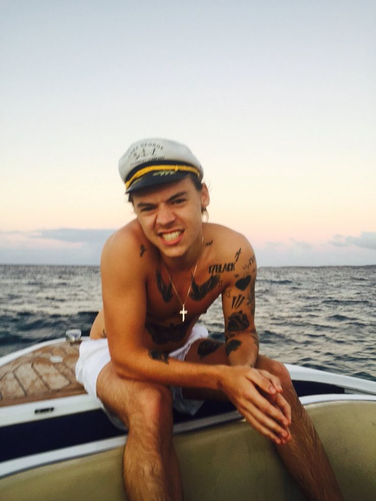 a man sitting on the back of a boat in the middle of the ocean smiling