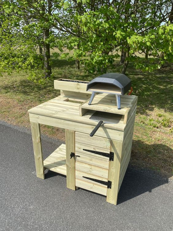 a wooden work bench with tools on it in the middle of a road next to some trees