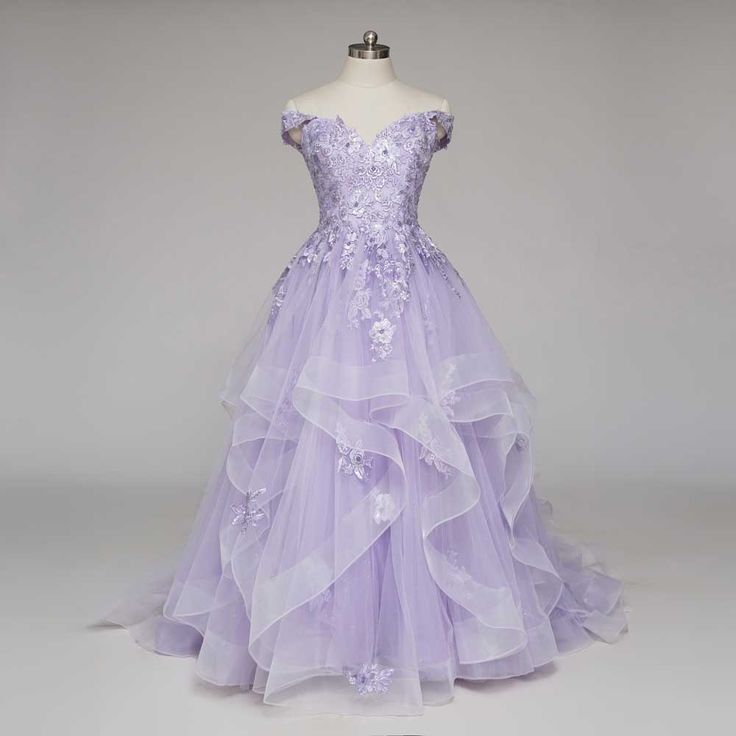 a purple dress with flowers on the bustle and ruffled skirt is displayed in front of a mannequin