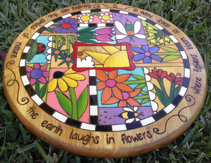 a colorful stained glass and wood plaque with flowers on it that says earth laughs in flowers