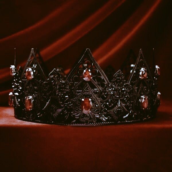 a black crown sitting on top of a red cloth