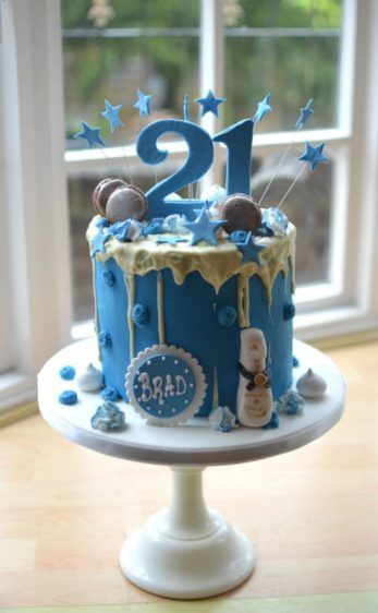 a blue birthday cake sitting on top of a wooden table in front of a window