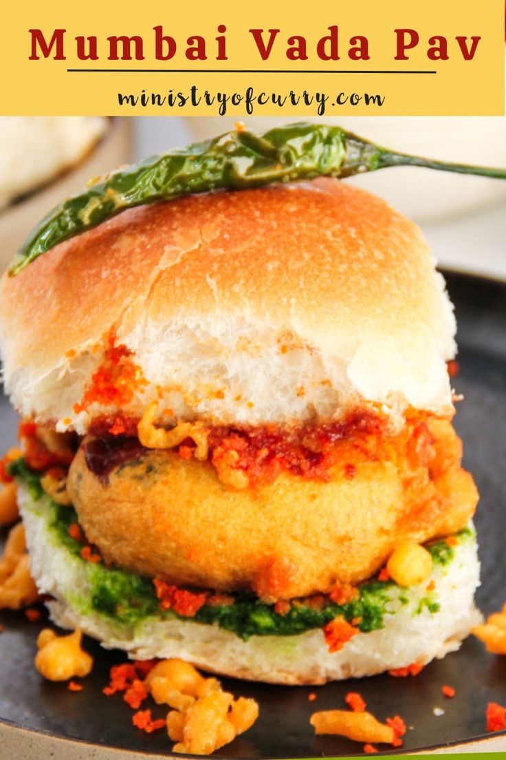 a close up of a sandwich on a plate with the words mumbai vada pav