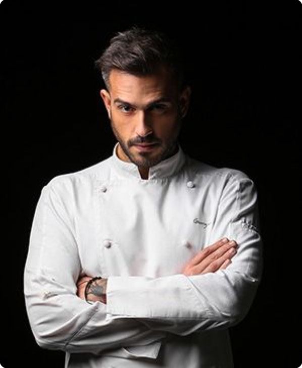 a man wearing a chef's coat and standing with his arms crossed