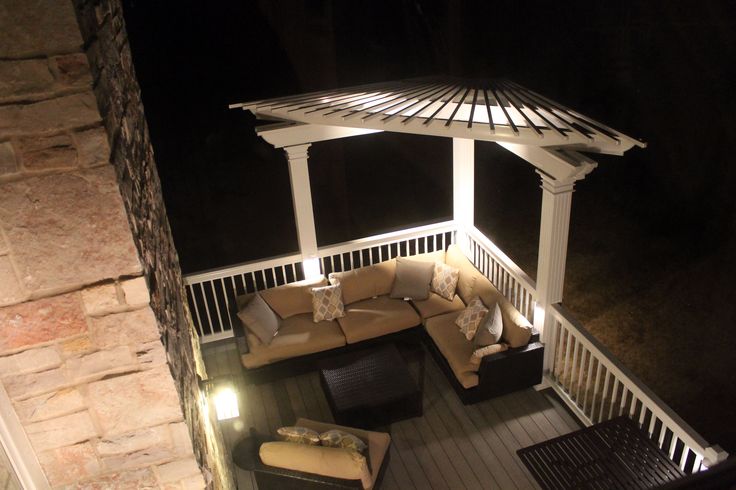 an outdoor living area lit up at night with furniture and lighting on the deck,