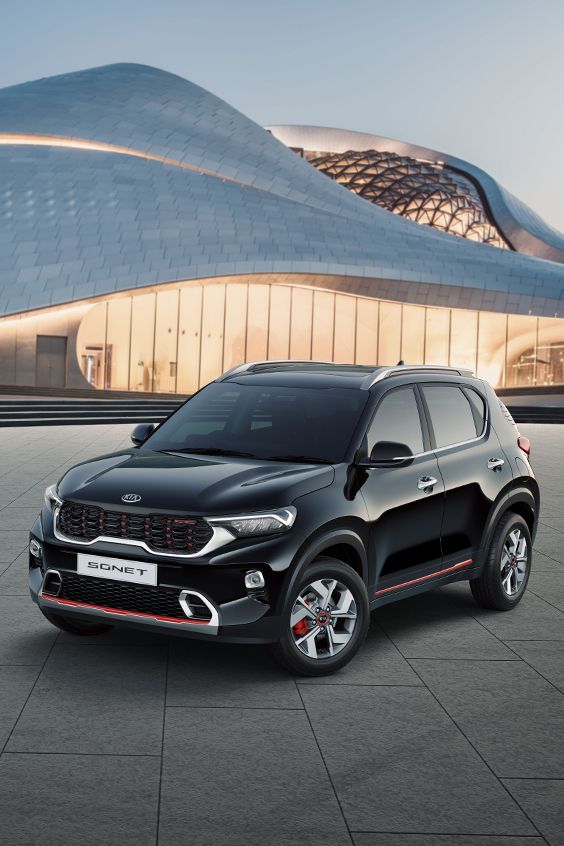 a black car parked in front of a building with a futuristic design on it's side