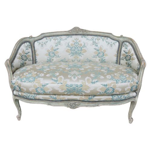 an antique style couch with blue and white floral fabric on it's armrests