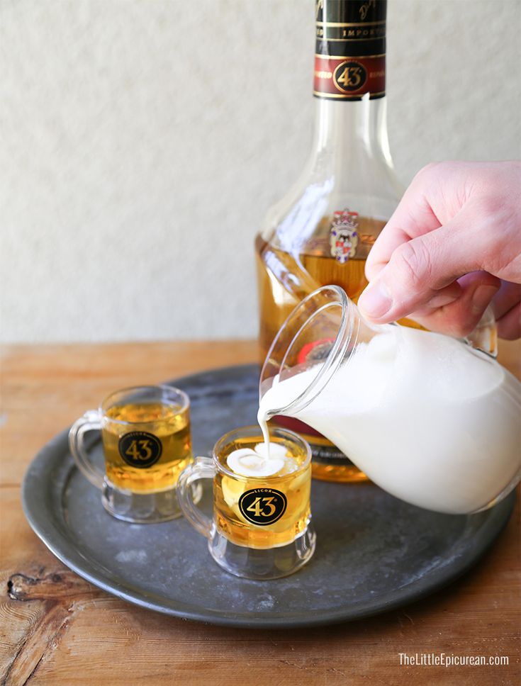 a person pouring white liquid into two glasses