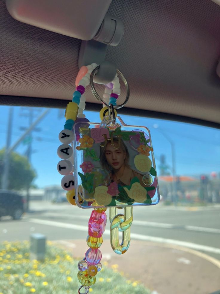 a car dashboard with a photo hanging from it's side window and flowers in the background