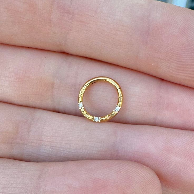 a person's hand holding a gold ring with three small diamonds on the inside