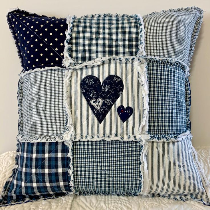 a blue and white patchwork pillow with two hearts on the front, one in the middle