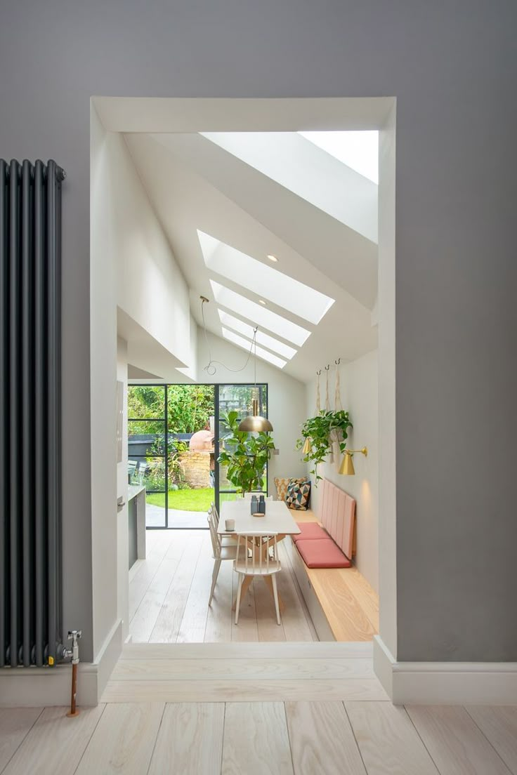 an open living room and dining area with skylights on the ceiling, wood flooring and white walls