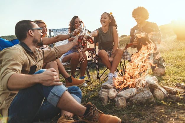 group of people sitting around a campfire laughing