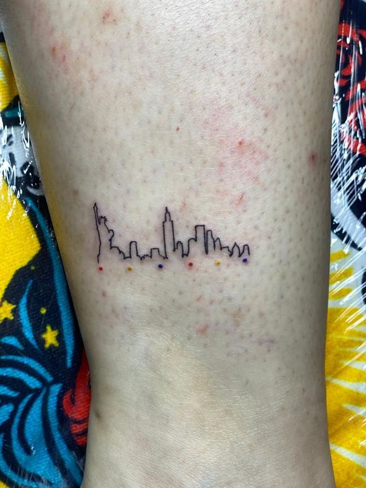 a small city skyline tattoo on the ankle