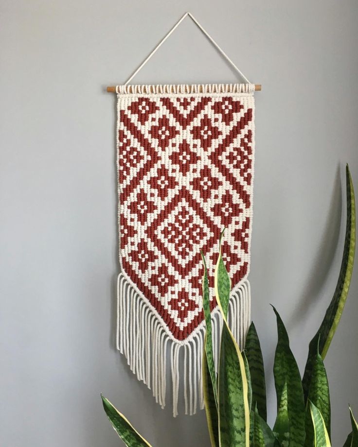 a red and white wall hanging next to a potted plant