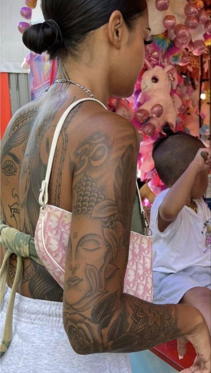 a woman with tattoos on her arms and chest standing next to a child holding an umbrella