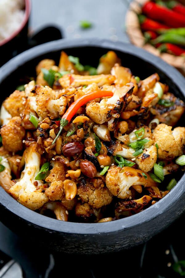 a black bowl filled with cauliflower and other vegetables on top of a table