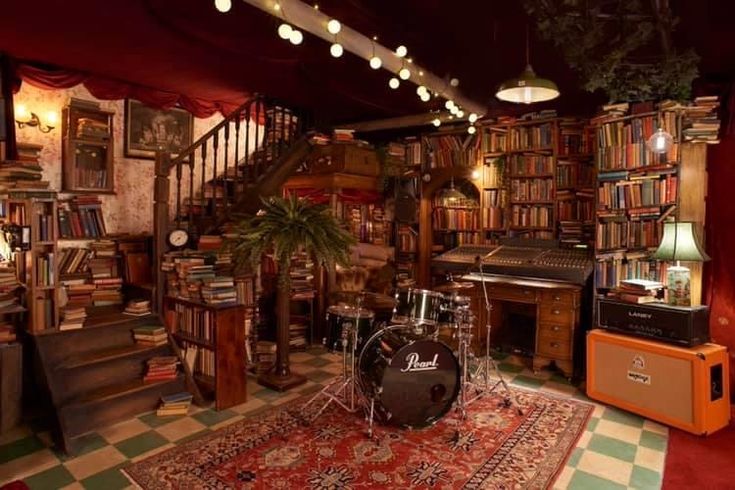 a room filled with lots of books and musical instruments on top of a red rug