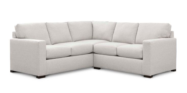 a white sectional couch sitting on top of a wooden floor