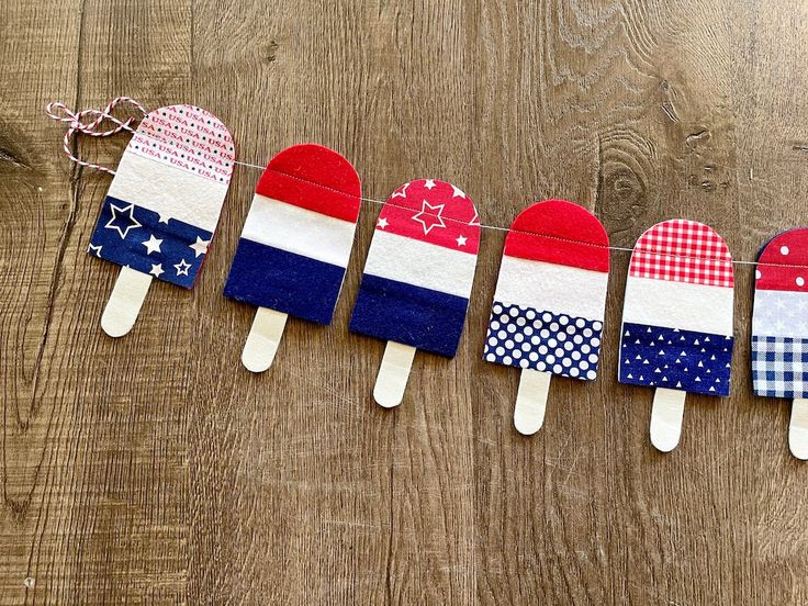 four popsicles decorated in the colors of the american flag are lined up on a string