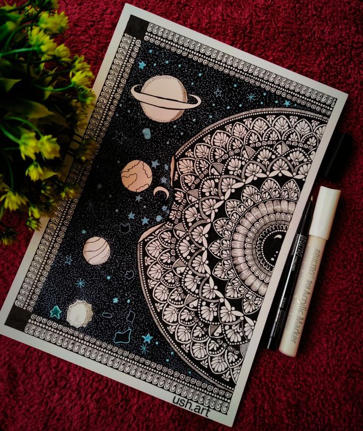 a drawing with space and planets on it next to some markers, pens and flowers