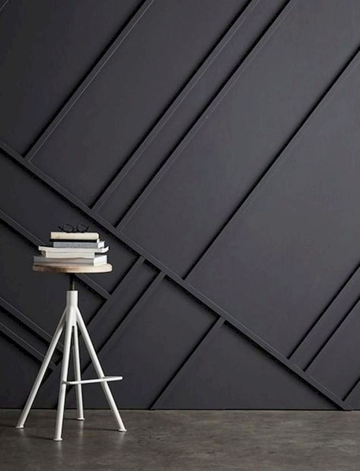 a white chair sitting next to a table with books on top of it in front of a black wall