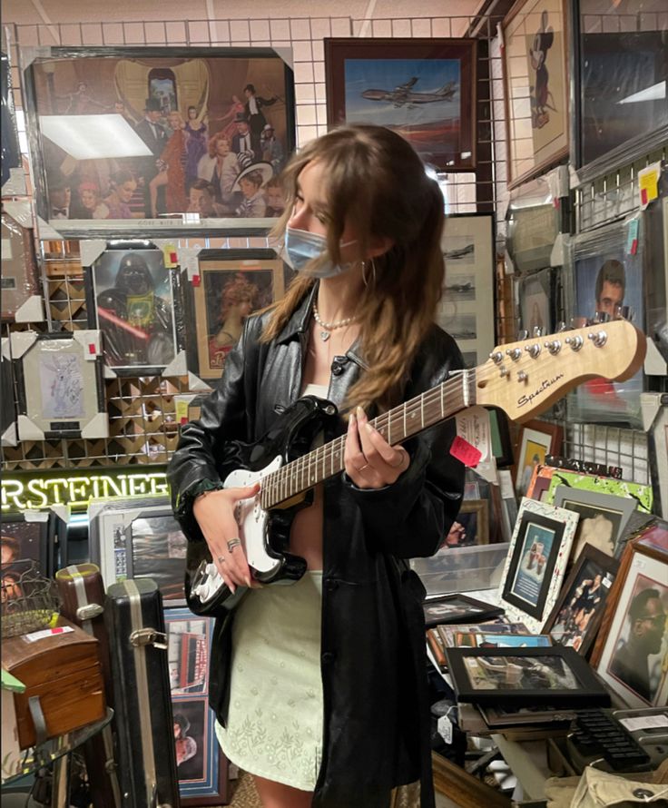 a woman is playing an electric guitar in a room full of pictures and other memorabilia