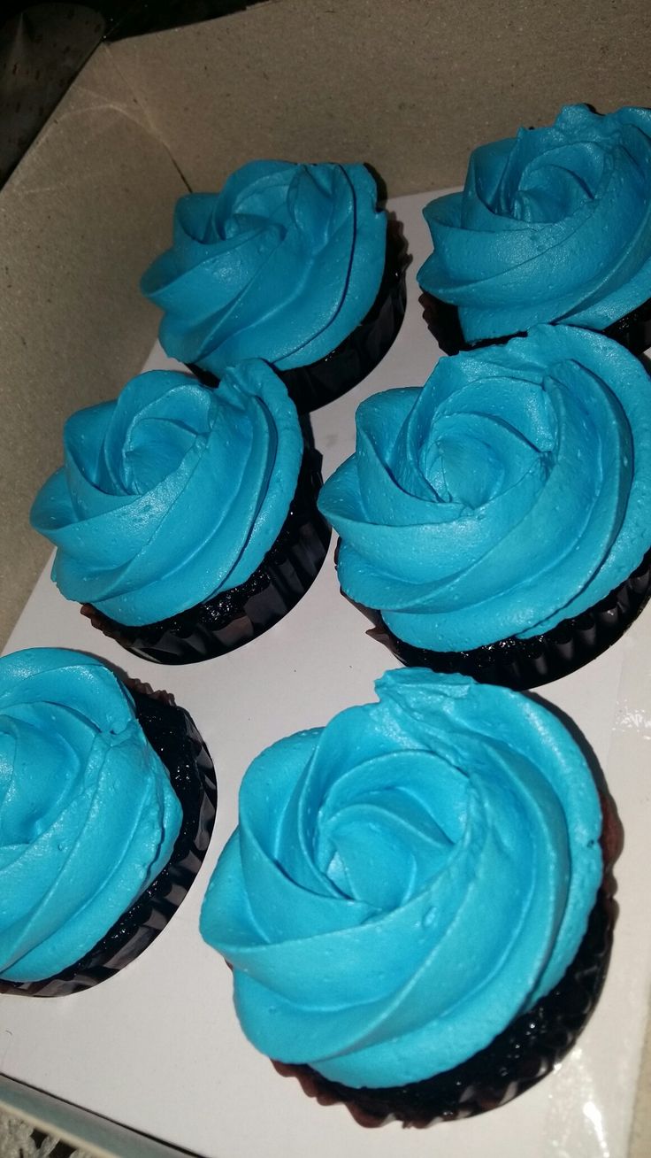 six cupcakes with blue frosting in a box