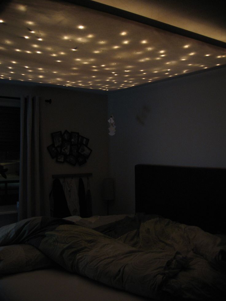 a bed room with a neatly made bed and lights on the ceiling