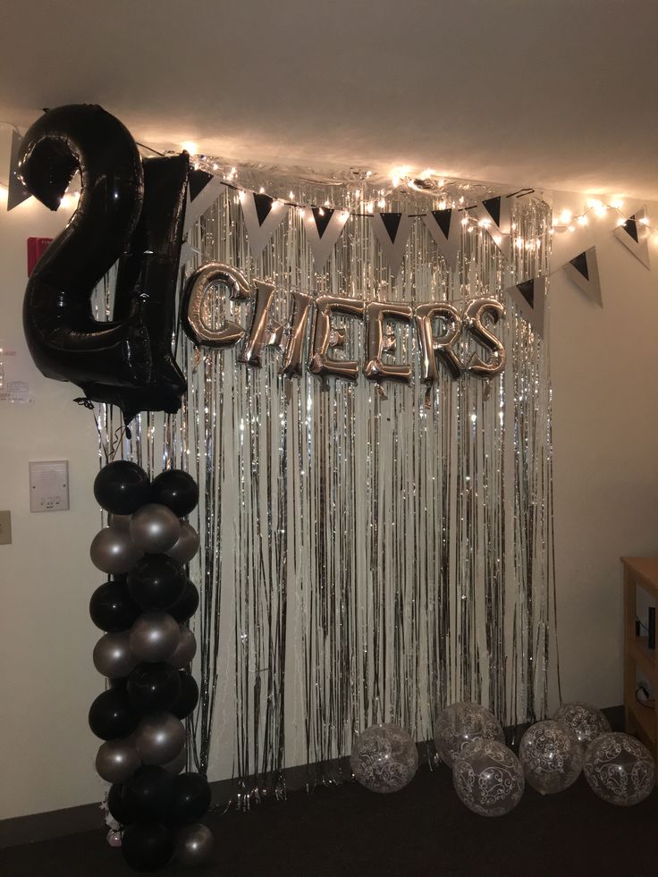 balloons and streamers are hanging from the ceiling in front of a curtain with letters that spell out cheers