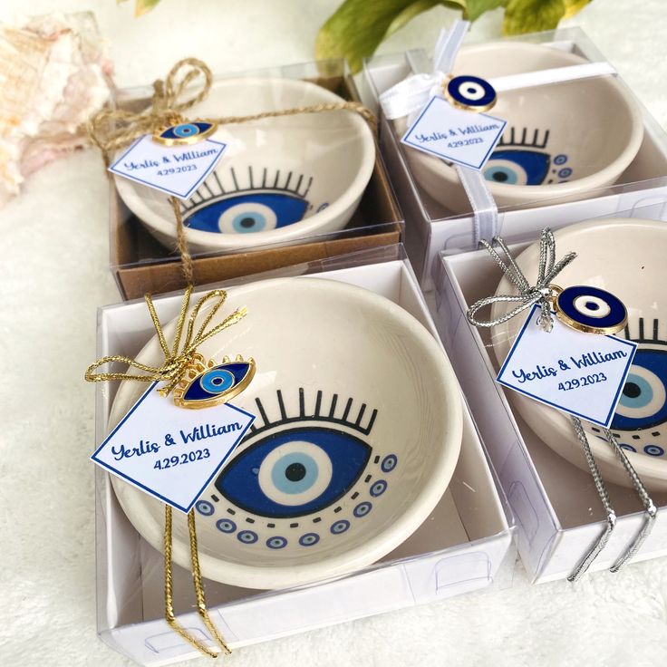 three blue and white bowls with tags tied to them in small boxes on a table