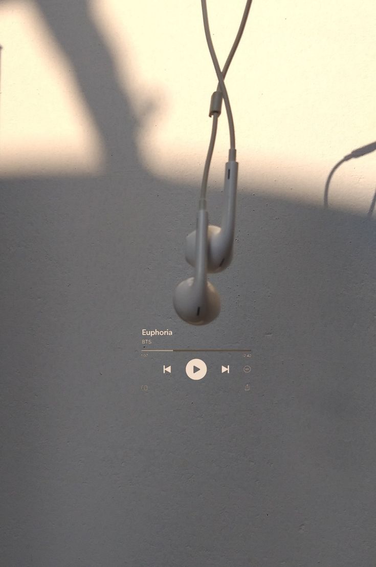 an mp3 player with headphones hanging from it's ear cord in front of a white wall