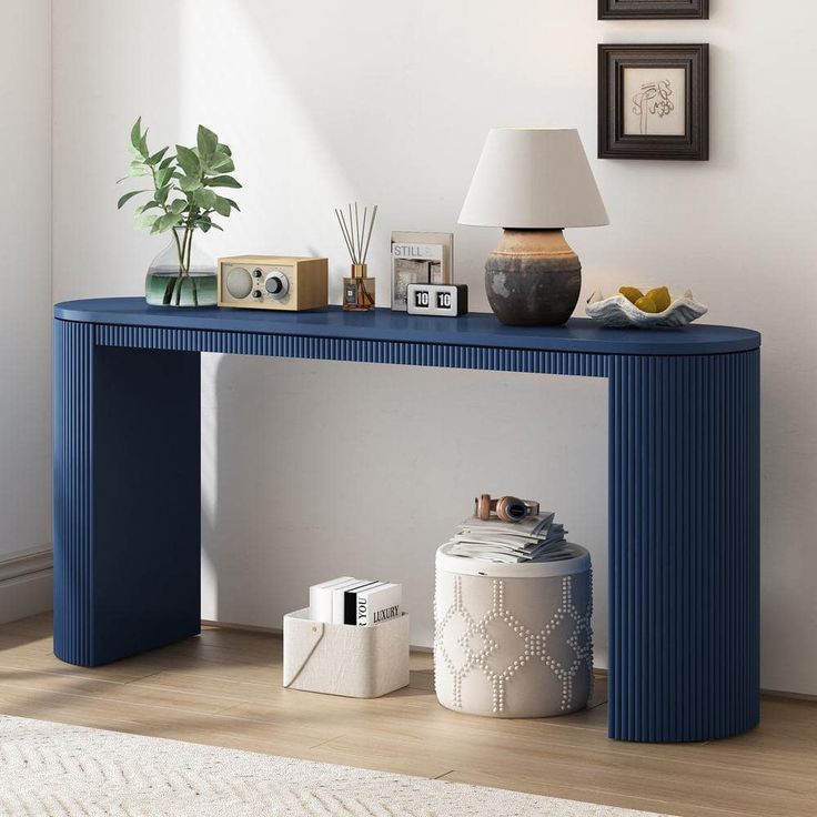 a blue console table sitting on top of a hard wood floor next to a lamp