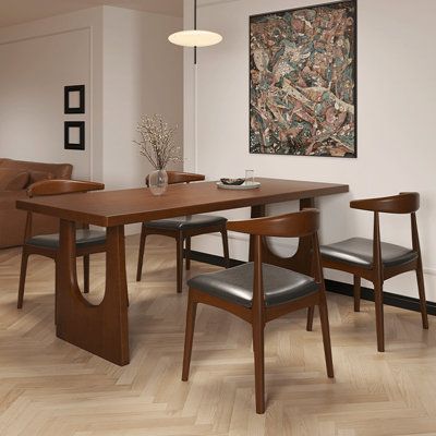 a dining room table with four chairs and a painting on the wall