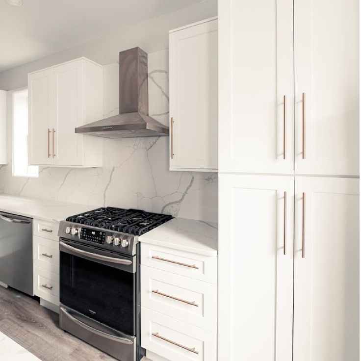 a kitchen with white cabinets and marble counter tops, stainless steel stove top oven and dishwasher