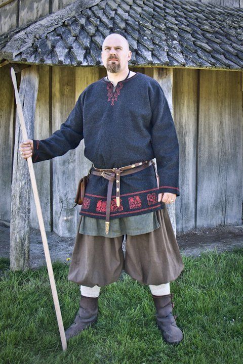 a man dressed in medieval clothing holding a stick