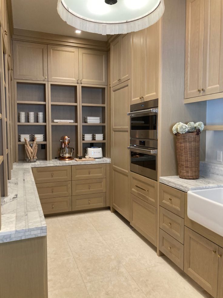 a large kitchen with wooden cabinets and white counter tops, along with a sink in the center